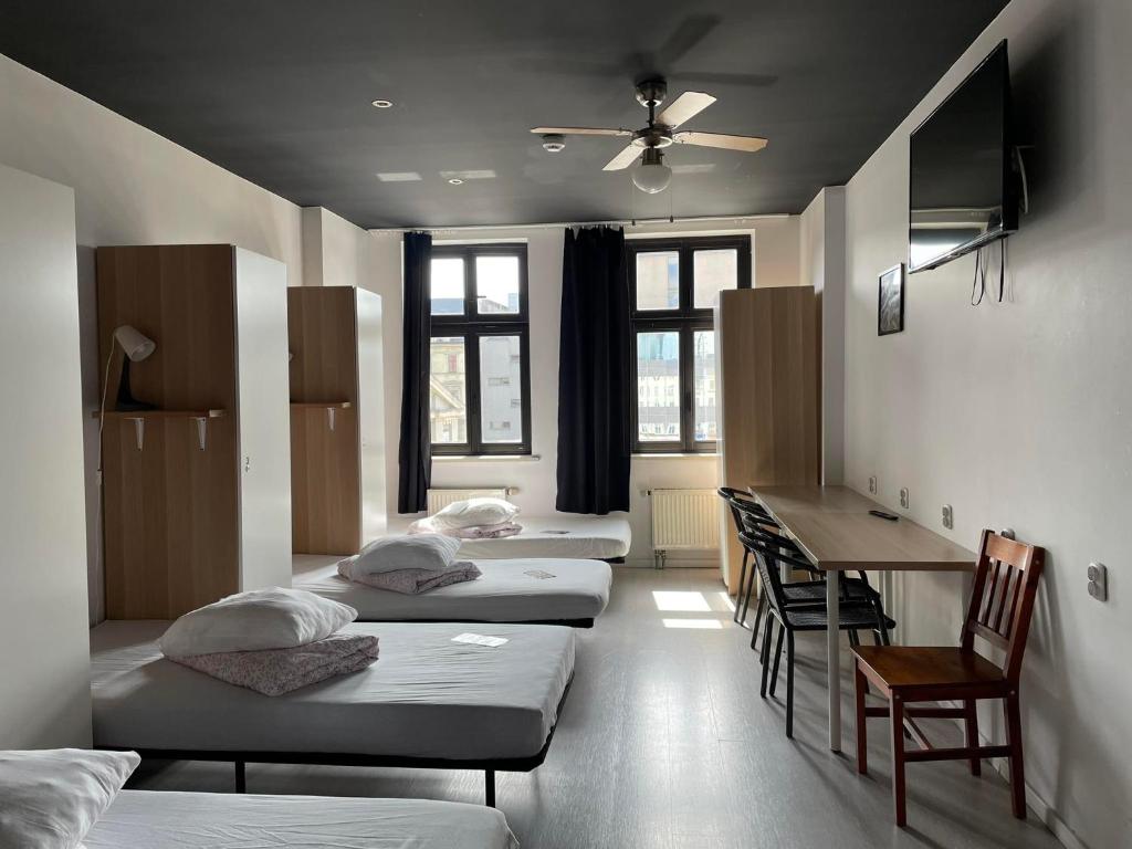 卡托维兹Hostel Kamienica Rynek 7的客房设有三张床、一张桌子和一张书桌