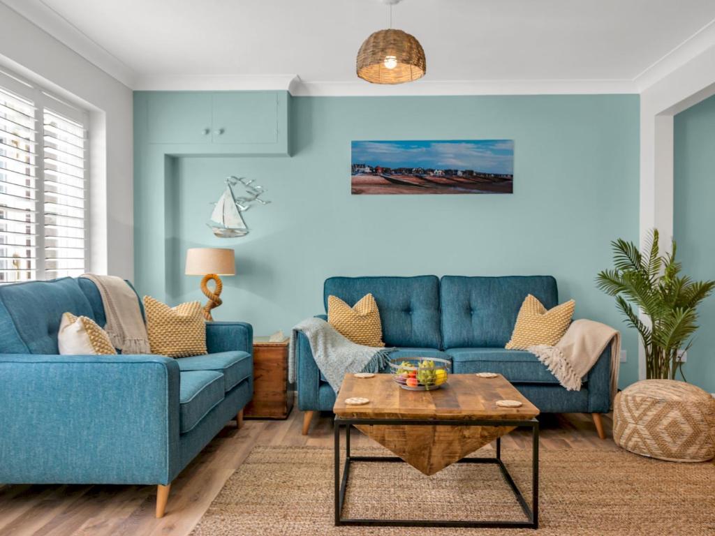 惠茨特布尔Pass the Keys Stunning 2 Bed House by the Sea的客厅配有2张蓝色的沙发和1张桌子