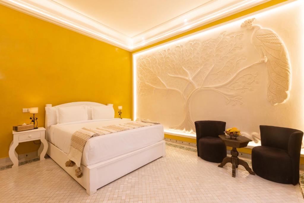 马拉喀什Albakech Boutique Hôtel & Spa的卧室配有白色的床和2把椅子