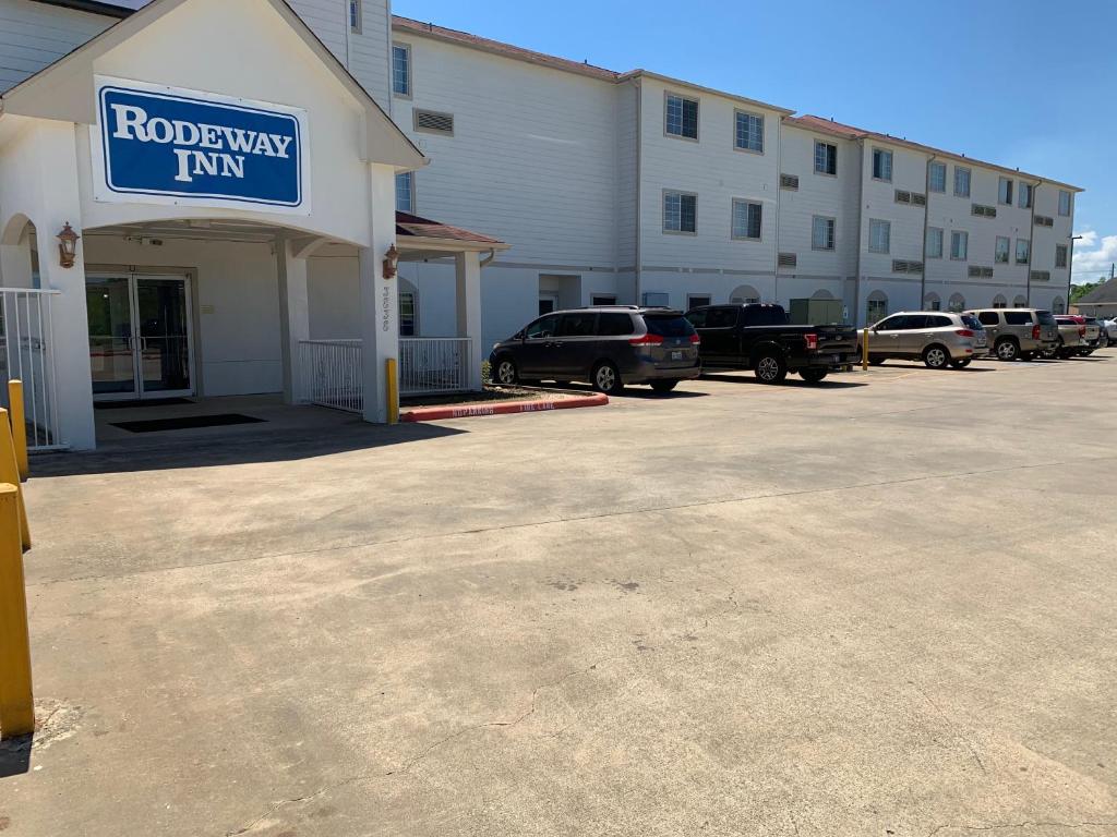 亚瑟港Rodeway Inn & Suites Port Arthur - Groves的停在酒店前停车场的一排汽车