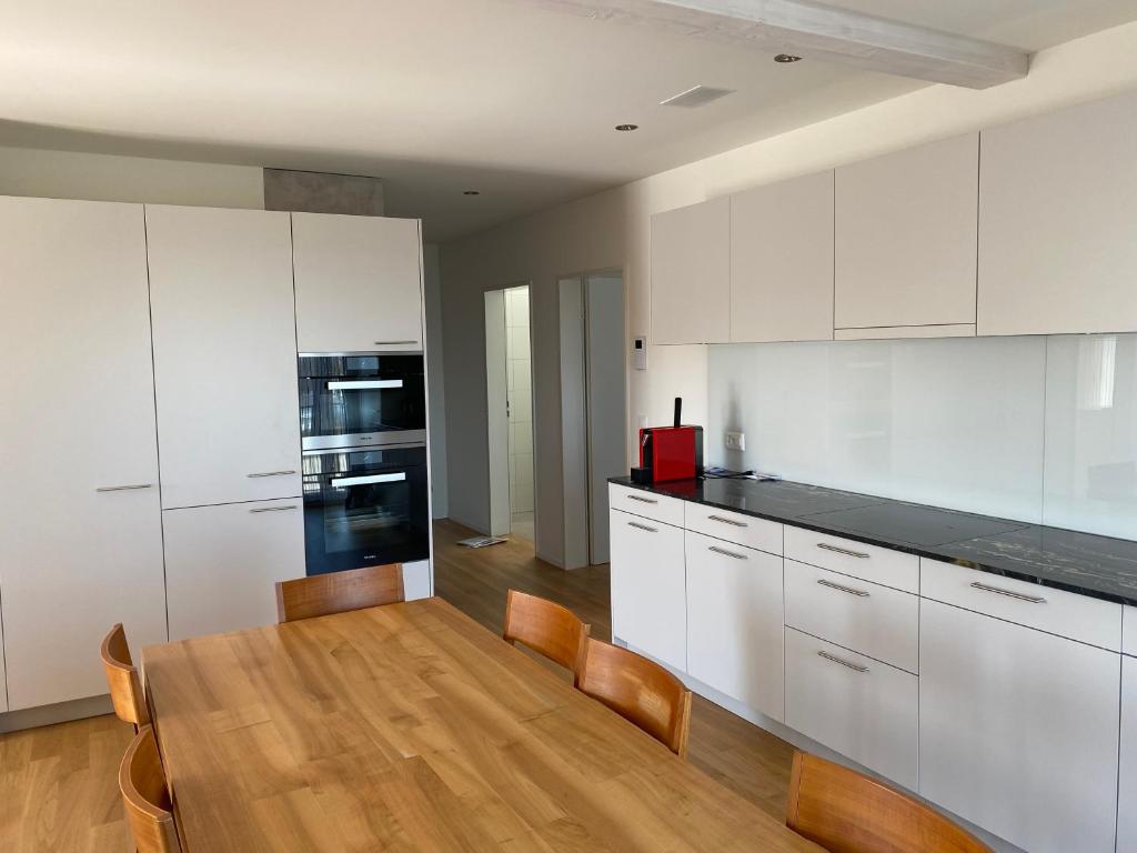 RickenbachMinergie的厨房配有白色橱柜和木桌