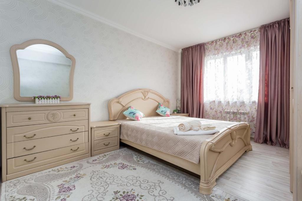 阿拉木图Светлая квартира рядом с парком Горького的一间卧室配有一张带梳妆台和镜子的床