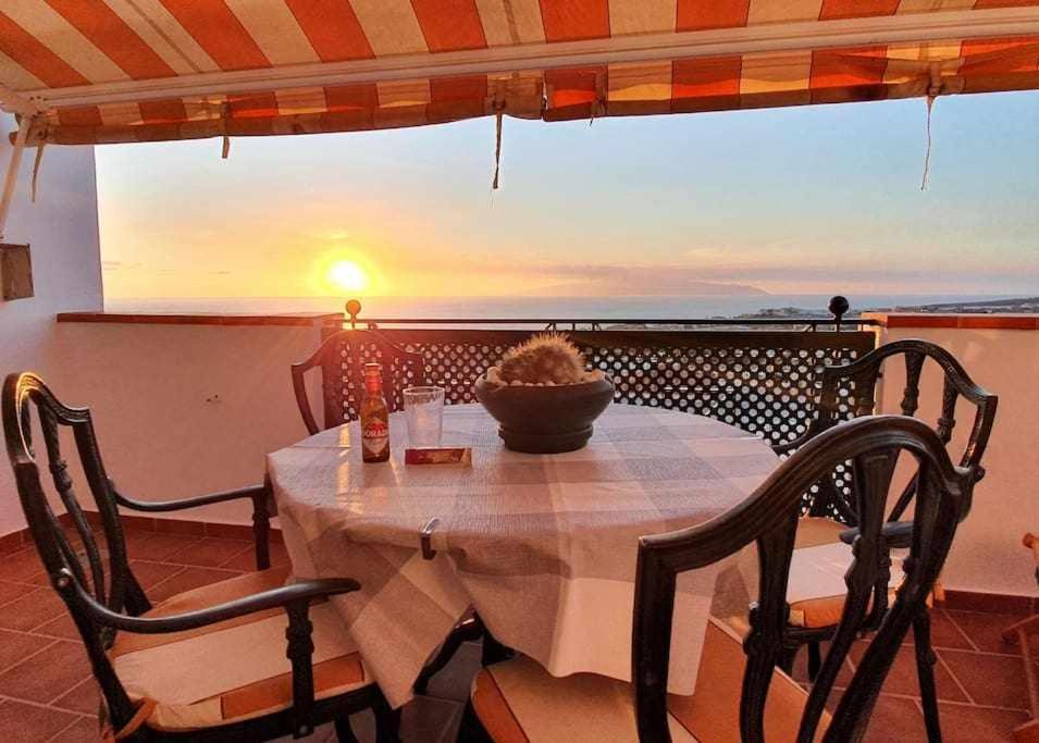阿德耶Apartamento Vista Atlántico的阳台上的桌椅享有日落美景