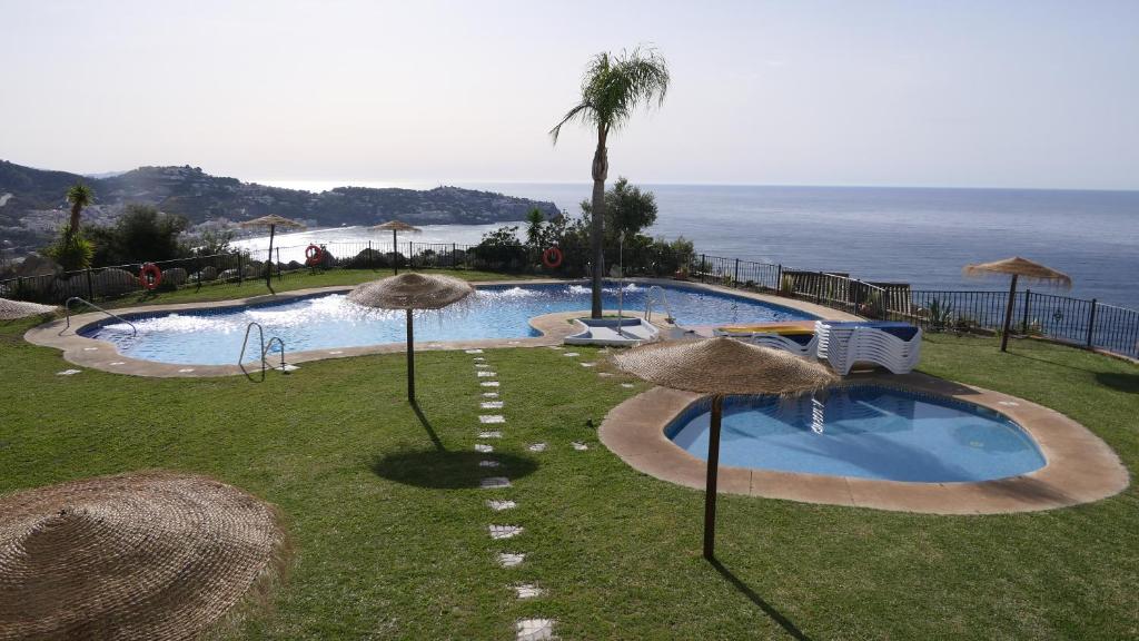 拉海瑞德拉Casa del Mar的一个带稻草遮阳伞和海洋的游泳池