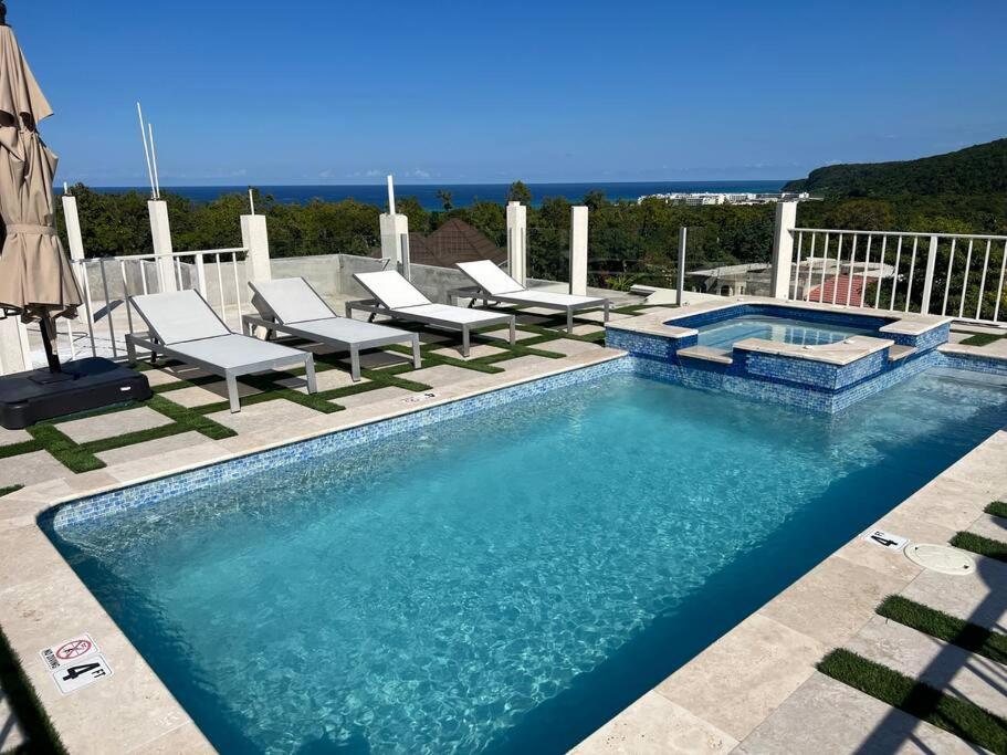 法尔茅斯Luxury 1 Bedroom & Rooftop Pool unit #2的游泳池旁带躺椅的游泳池