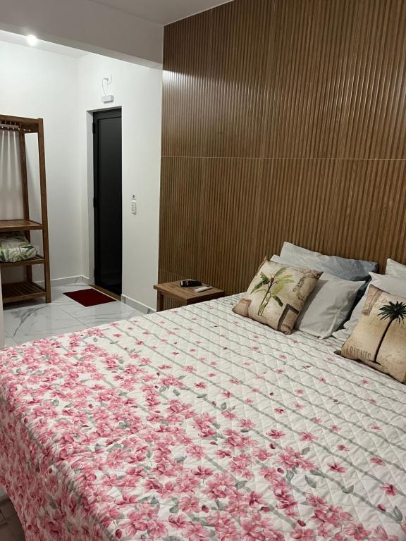 瓜拉图巴Pousada Maria Helena的一间卧室配有一张带花卉图案的毯子的大床