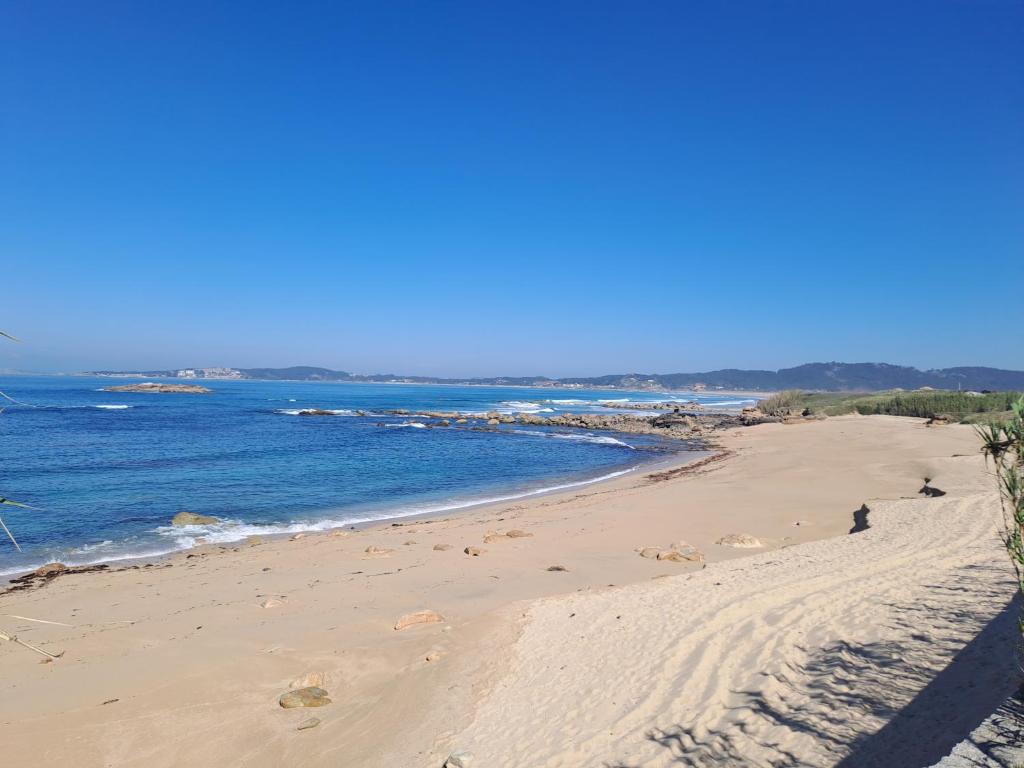 阿兰扎达Desconectaengalicia La Lanzada, a pie de playa的海滩与大海相映成趣