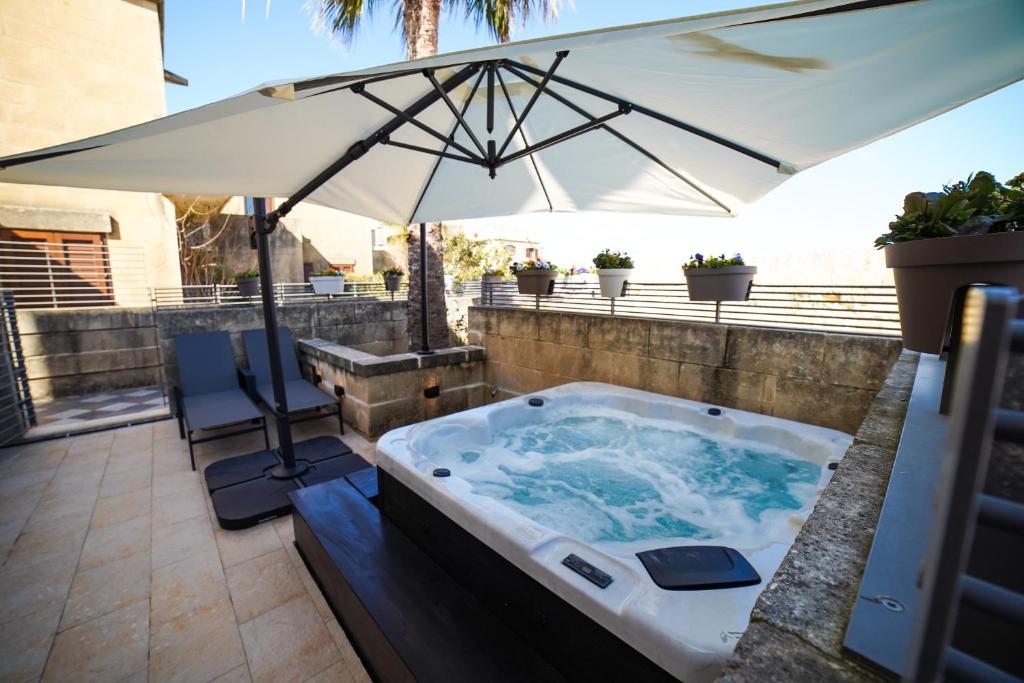 MġarrHarbour Views Duplex Maisonette with Jacuzzi Hot tub的庭院内带遮阳伞的热水浴池