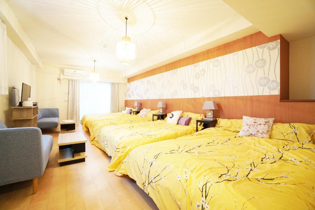 大阪MATATABI STAY Daikokucho的酒店客房,设有三张带黄床单的床