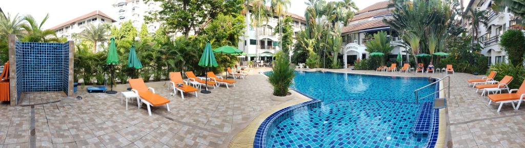 芭堤雅市中心Oasis Rentals, Diana Estate, Pattaya的酒店旁的游泳池配有椅子和遮阳伞