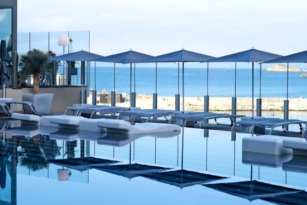 邦多勒Thalazur Bandol Ile Rousse - Hôtel & Spa的一个带椅子和遮阳伞的游泳池