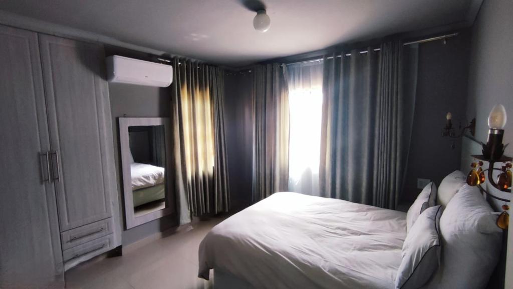 焦济尼Labas Travellers Guesthouse的卧室配有白色的床和镜子