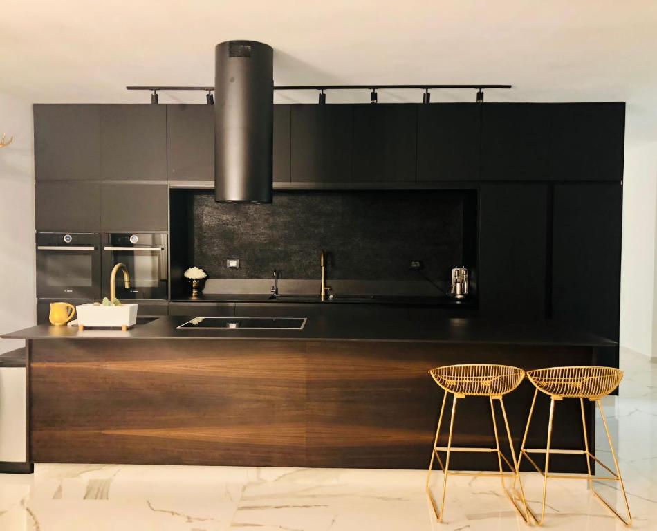 雷霍沃特Boutique Penthouse by Weizmann - פנטהאוס בוטיק的厨房配有黑色橱柜、水槽和2把椅子