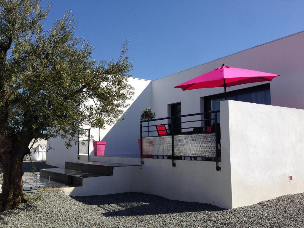 贝济耶新城奥西利亚度假屋的白色的房子,配有粉红色的伞和楼梯