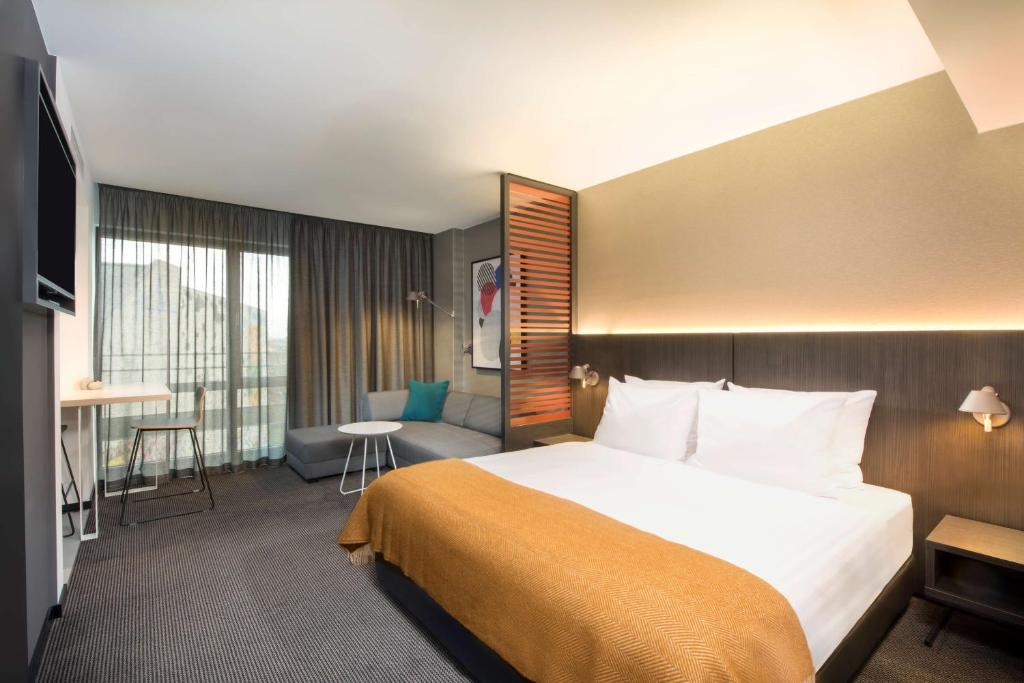 莱比锡莱比锡阿迪娜公寓酒店的酒店客房设有一张大床和一张沙发。