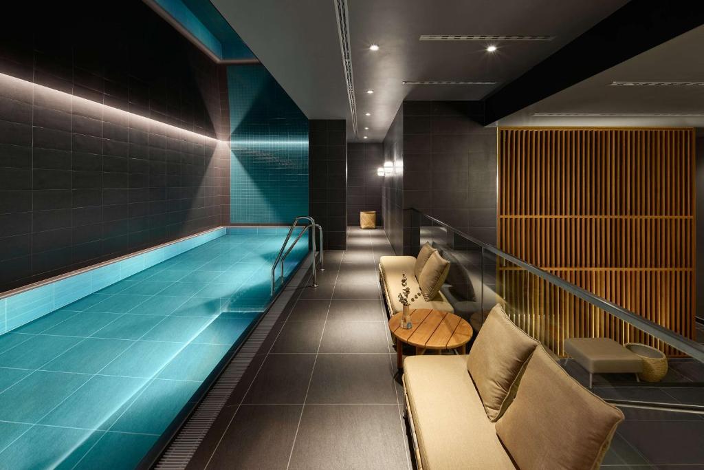 斯图加特Adina Apartment Hotel Stuttgart的一座带椅子和沙发的建筑中的游泳池