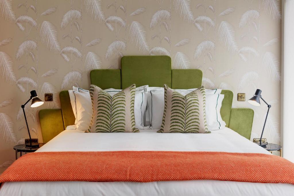 布罗姆利Brama的一张带橙色毯子和白色枕头的床