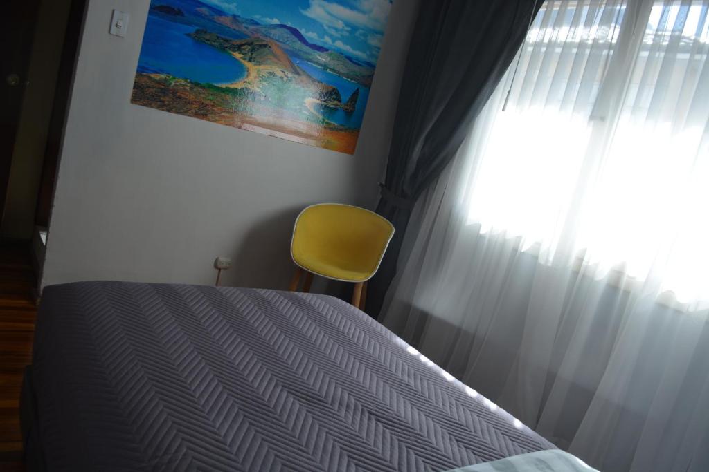 基多Blue house La Floresta的一间卧室配有一张带黄椅的床和窗户