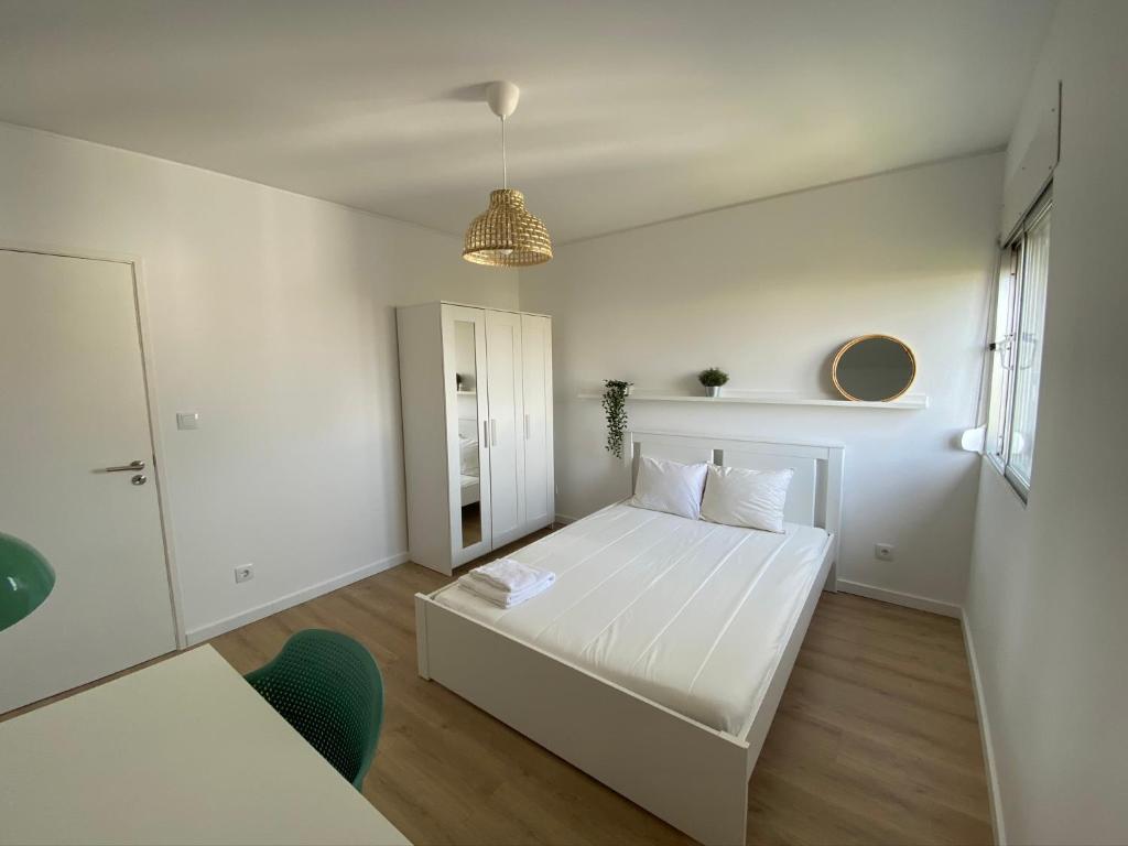 奥埃拉斯Carcavelos Beach walking distance room in shared apartment的白色的卧室设有白色的床和窗户。