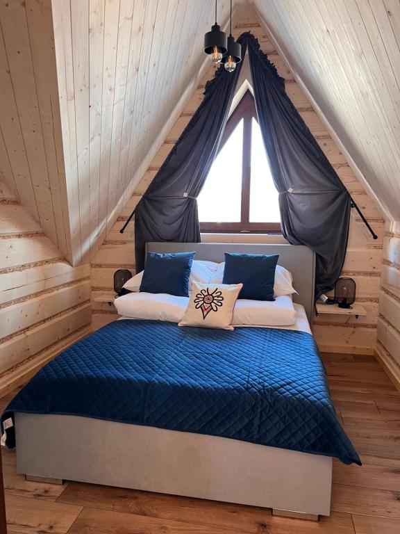扎科帕内Liliowa Willa的一间卧室配有一张带蓝色床单的床和一扇窗户。