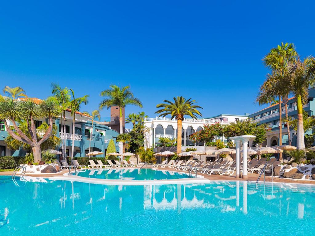 阿德耶阿德里安科隆瓜纳哈尼成人酒店的一个带椅子和棕榈树的大型游泳池