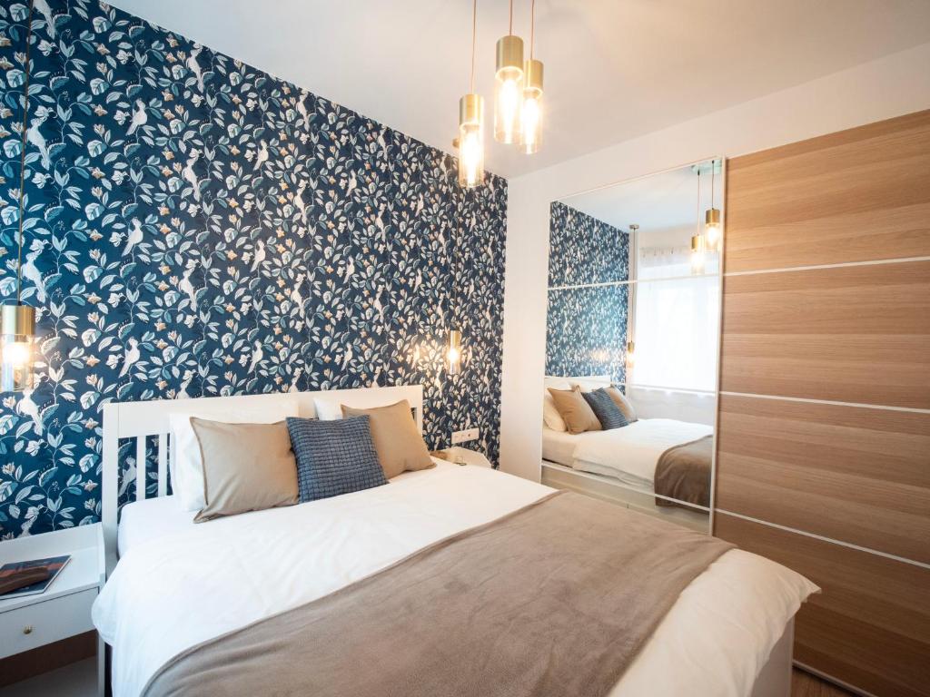布达佩斯Blue Bird Citadel Apartment的一间卧室配有一张带蓝色和白色花卉图案壁纸的床