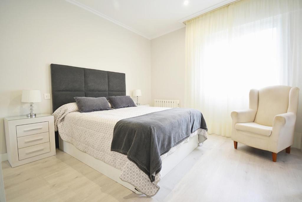 桑亨霍Apartamento en pleno centro de Portonovo, Sanxenxo的白色卧室配有床和椅子