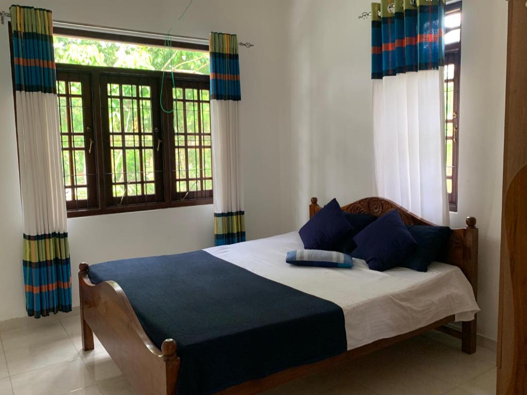 本托塔Tranquil Private Villa near Bentota Beach的一间卧室配有一张带蓝色枕头的床和窗户。