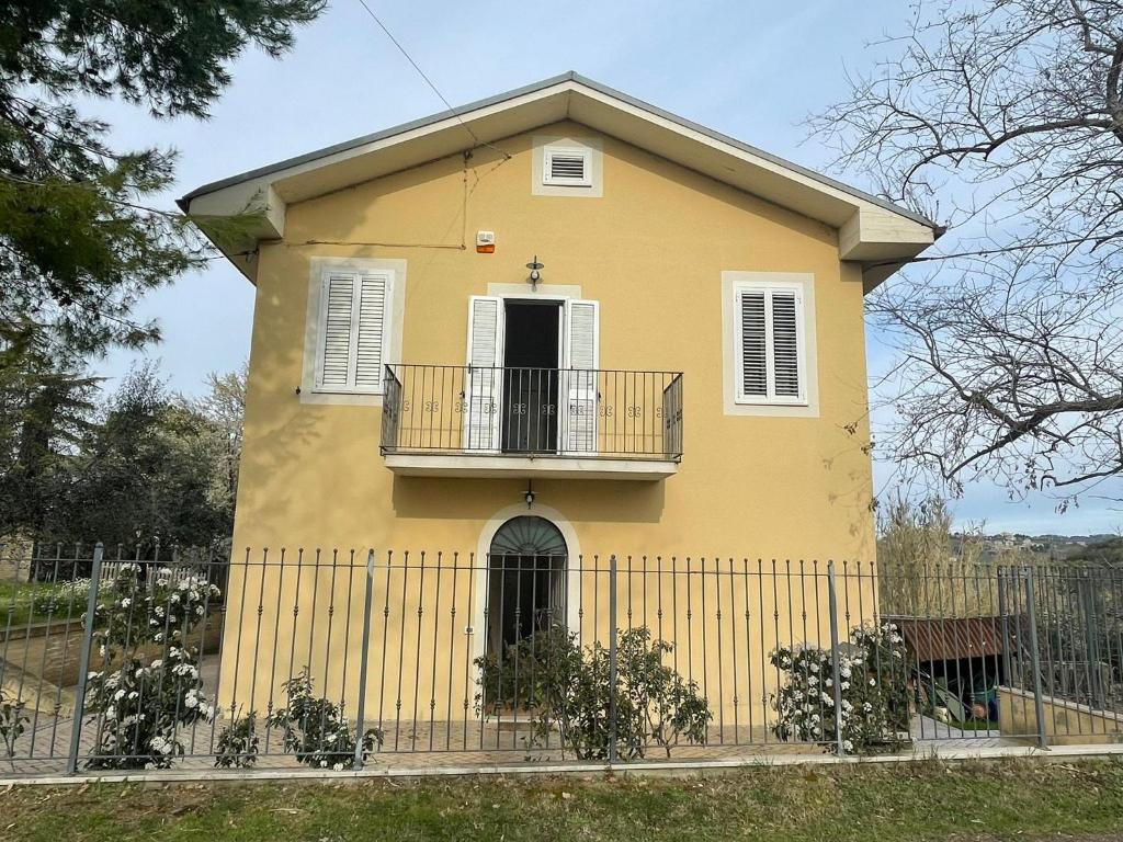 阿夸维瓦皮切纳Casa Forola Holiday House的黄色房屋设有阳台和围栏
