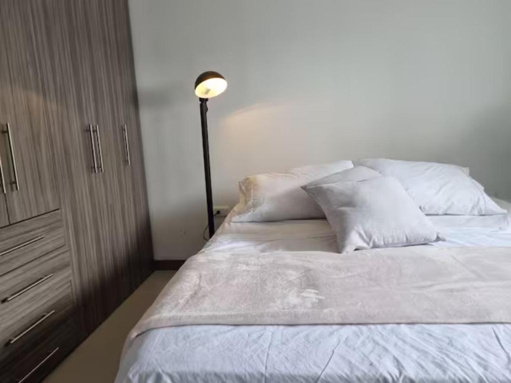 佛罗里达布兰卡Apto Botero 1308 - WAIWA HOST的一张带白色床单和枕头的床,旁边是台灯