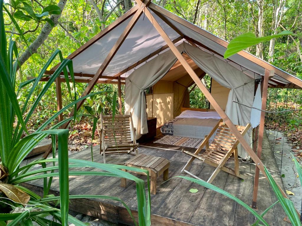 TandulujanggaCamp Tarimbang的树林里带椅子和床的帐篷