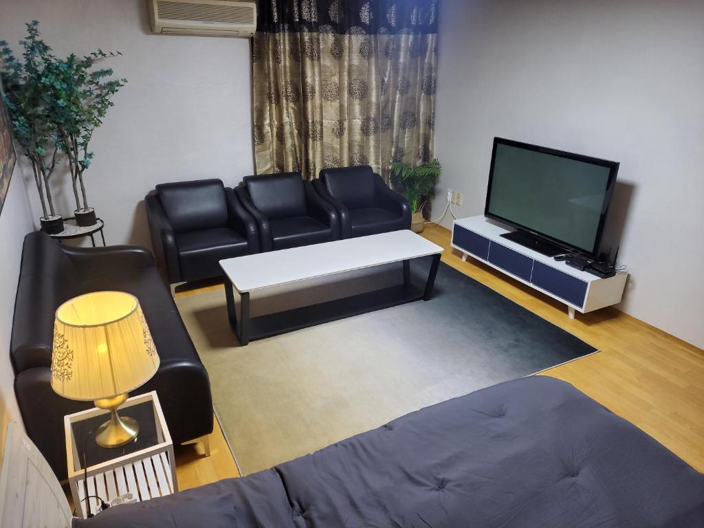 首尔Spacious Master Suite的客厅配有黑色皮革家具和平面电视