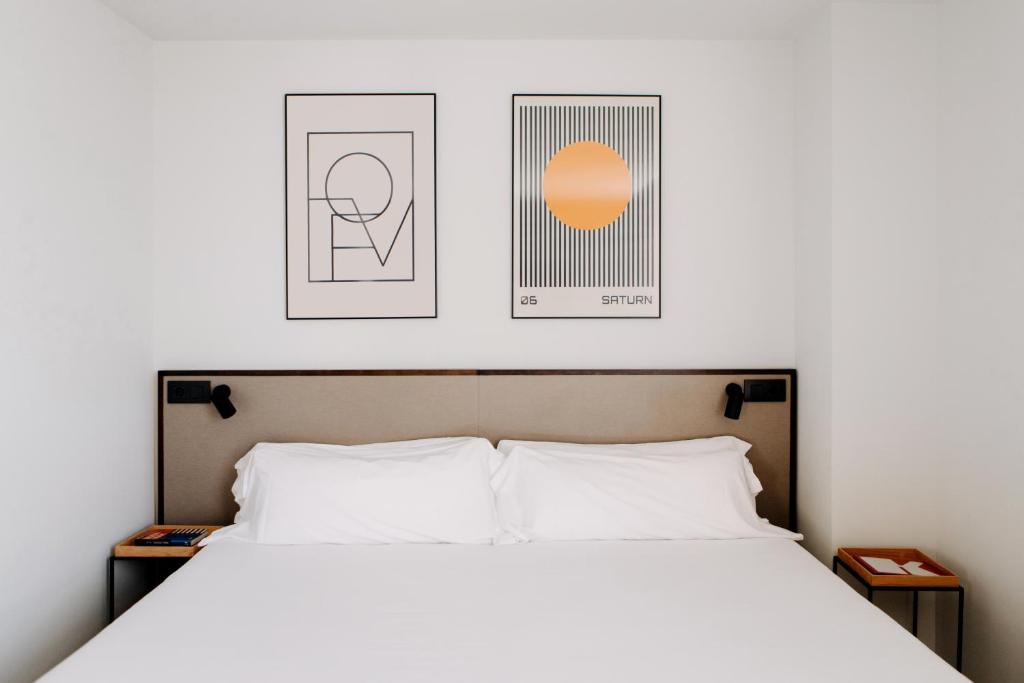 瓦伦西亚克莱默酒店的卧室配有一张床,墙上挂有两张照片