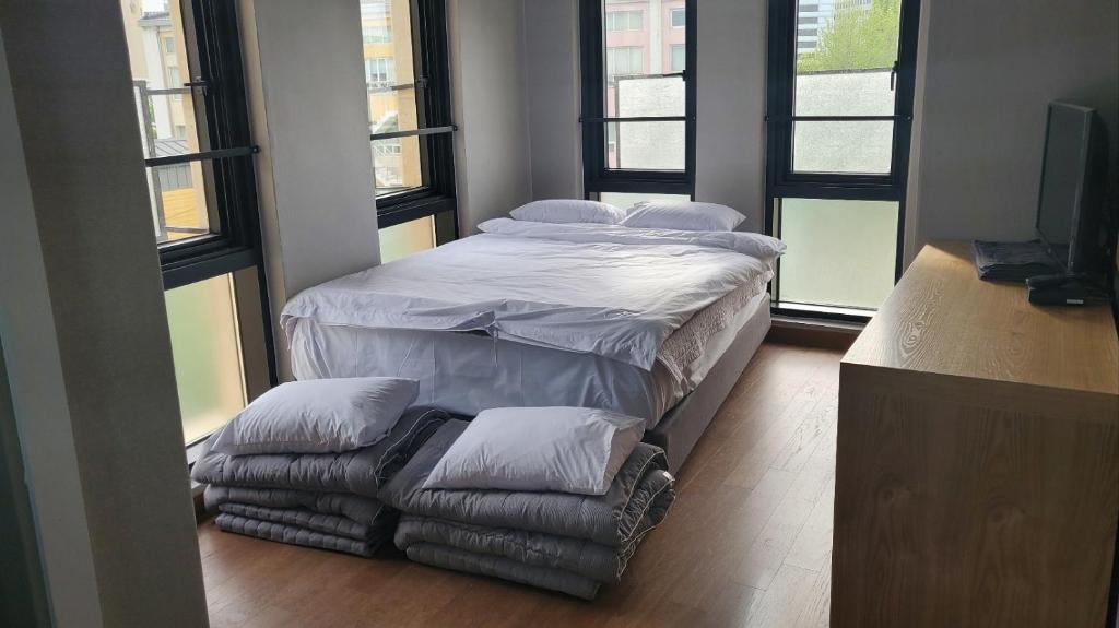 首尔J.Hill House的带窗户的客房内的一张带枕头的大床和椅子