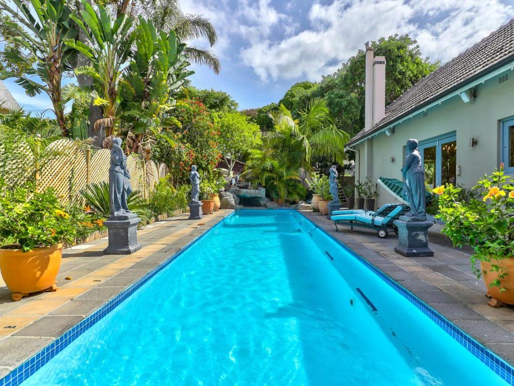 开普敦Villa Jesdene的棕榈树房子后院的游泳池