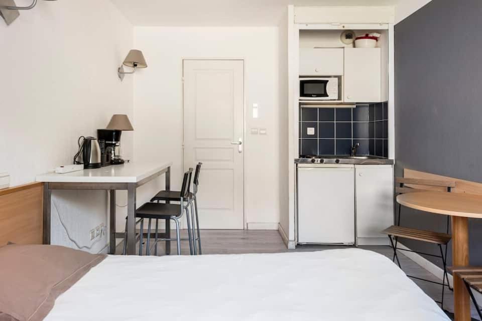 马赛马赛普拉多斐瑞尔公寓式酒店的一间卧室配有一张床,厨房配有桌子