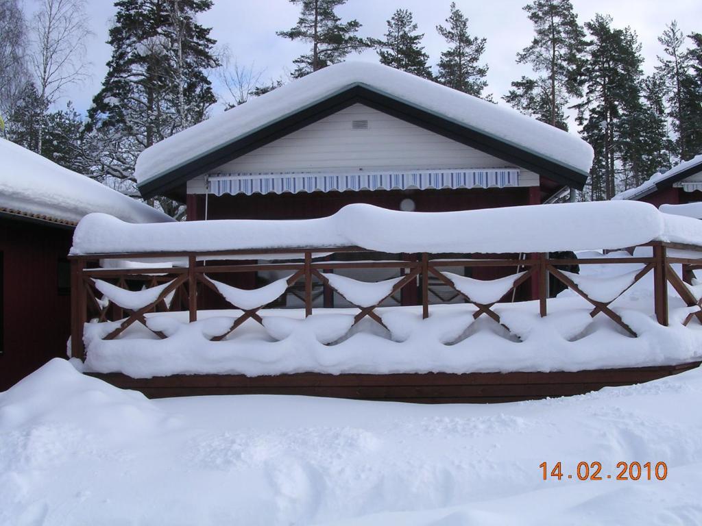 KisaFöllingen stugan的雪覆盖的房屋,有栅栏