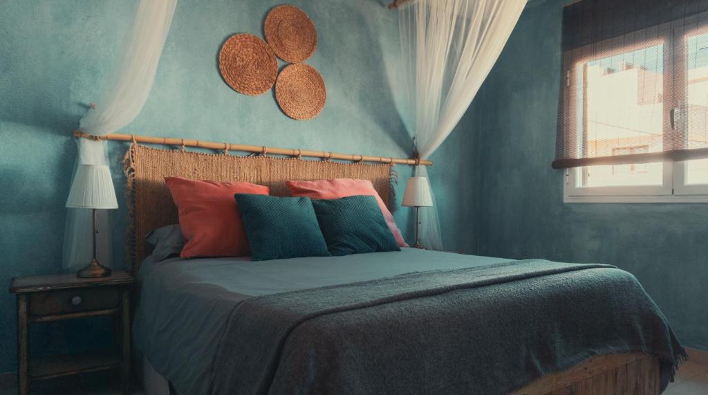 伊斯费古耶拉尔海滩Hostal Esfigueral的一间卧室配有一张蓝色墙壁的床和一扇窗户