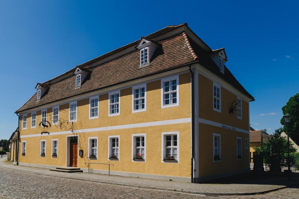DrehnaGasthof Zum Hirsch的一条黄色的街道上,有棕色屋顶的建筑