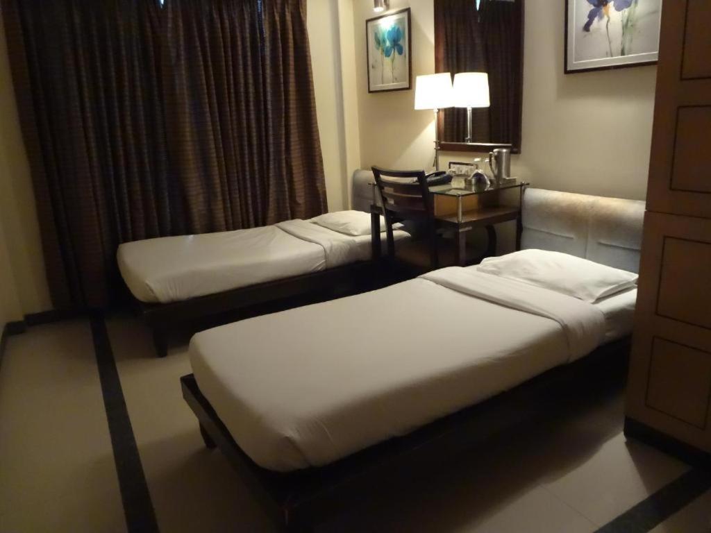 孟买HOTEL SAPNA MARINE的酒店客房配有两张床和一张桌子及椅子
