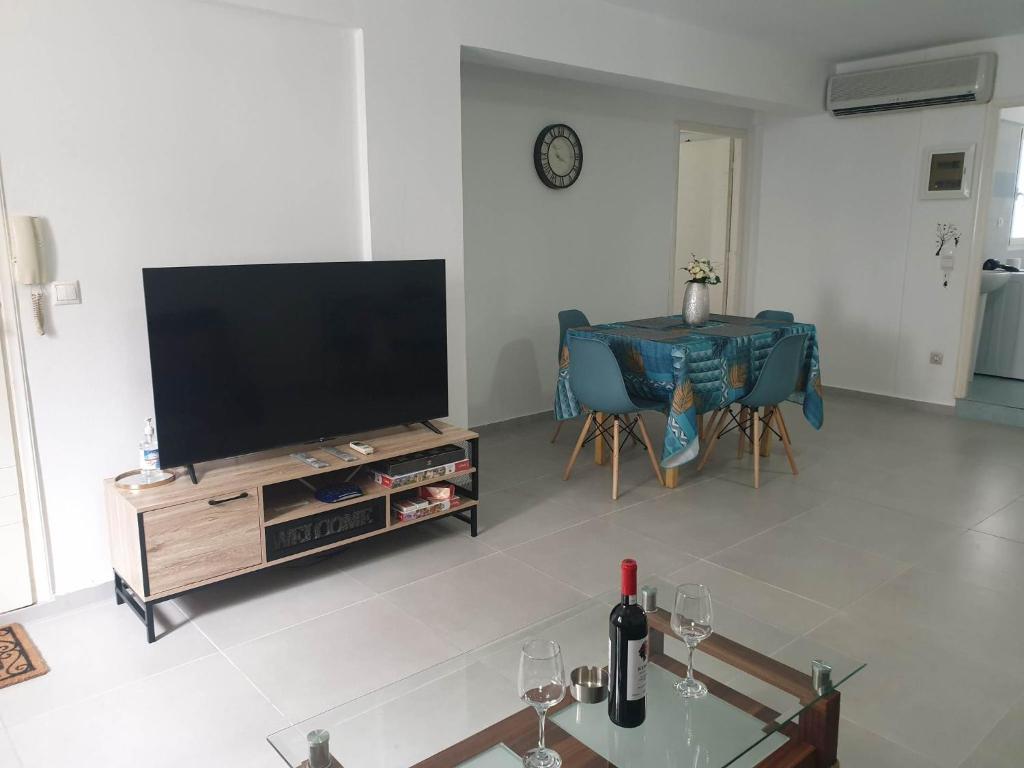 MoíraiNikolas Family Apartments的客厅配有平面电视和桌子。