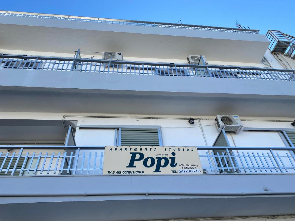 科斯镇Popi Studios的白色的建筑,阳台上有标志