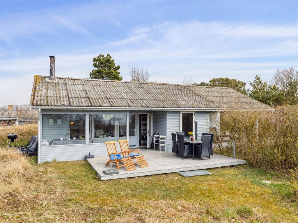 奥基克比Holiday Home Bondi - 150m from the sea in Bornholm by Interhome的白色的小小屋设有甲板和椅子