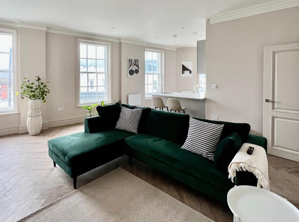 莱瑟姆-圣安妮The Apartments Lytham Square的一间带绿色沙发的客厅和一间厨房