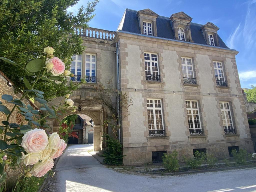 里摩日La Villa Beaupeyrat - Apparthôtels de charme dans bâtisse de caractère的一座古老的石头建筑,有拱门和粉红色的玫瑰