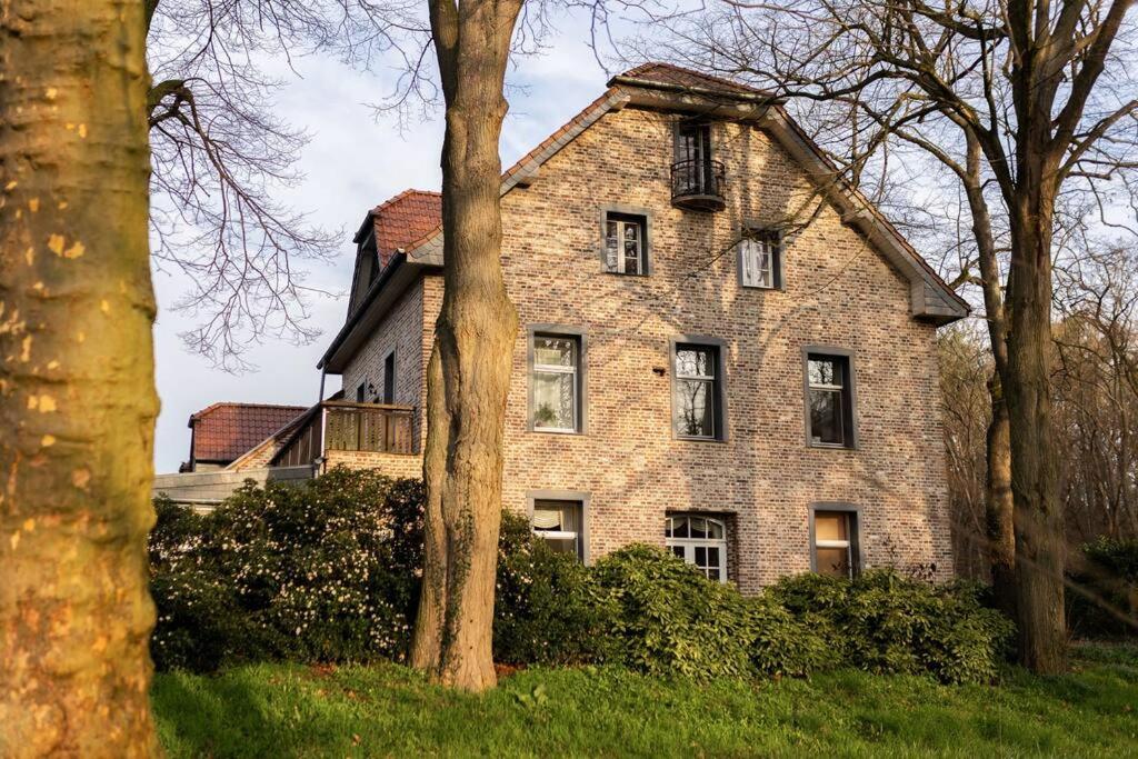 韦策Ferienhof in Weeze-Wemb的一座老砖房,前面有树木