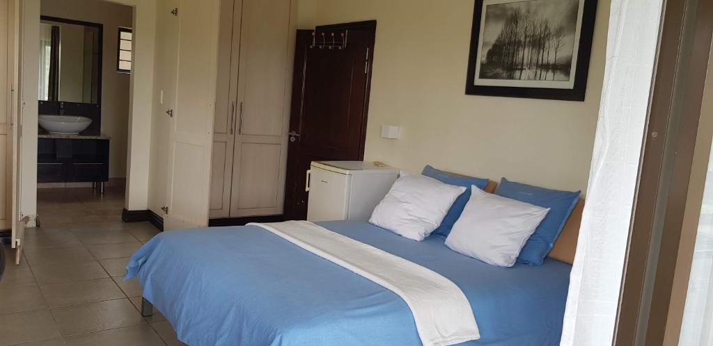德班JV guesthouse的一间卧室配有一张带蓝色床单和白色枕头的床。