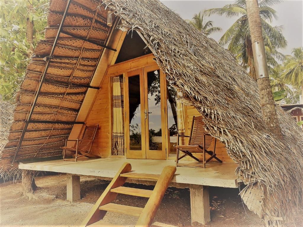阿努拉德普勒Monara Arana Farm Resort的小小屋设有两把椅子和门廊