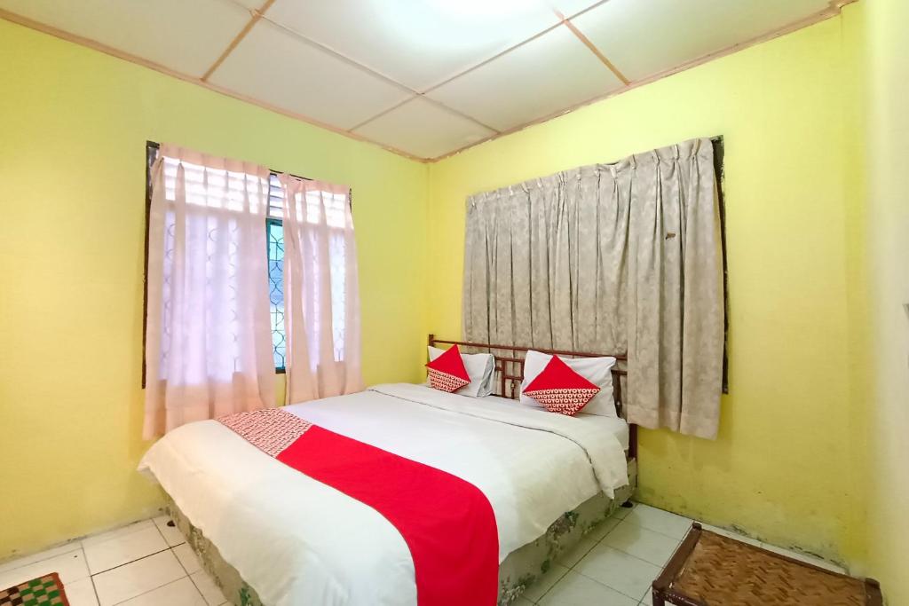 巴拉巴特OYO 92503 Penginapan & Villa Sirait的一间卧室配有红色和白色枕头的床