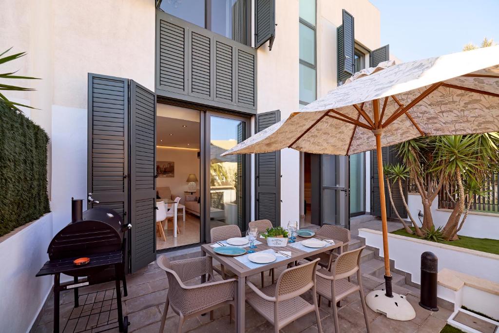 拉萨维纳Apartamento tríplex nuevo en la Savina的天井配有带遮阳伞和烧烤架的桌子。
